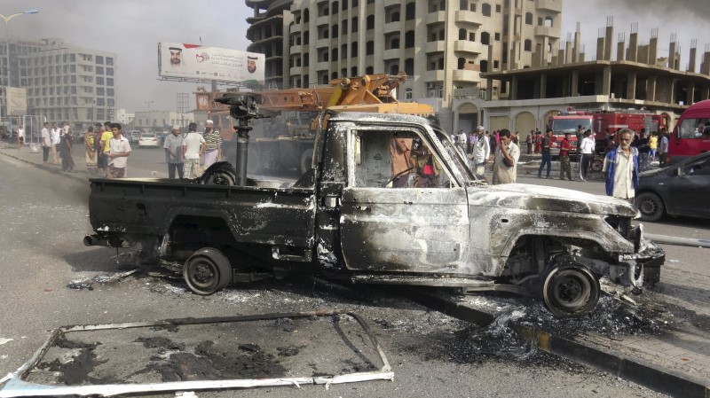 © Reuters. People look at a burnt-out police patrol vehicle after clashes in Yemen's southern port city of Aden