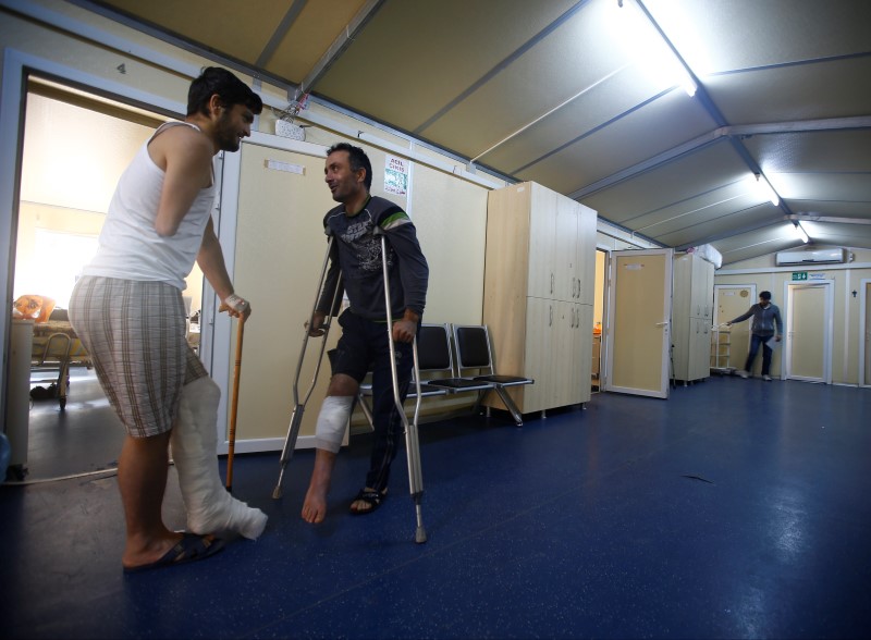 © Reuters. Injured Syrian fighters chat along the corridor of a small clinic near the Turkish-Syrian border in the southeastern city of Kilis