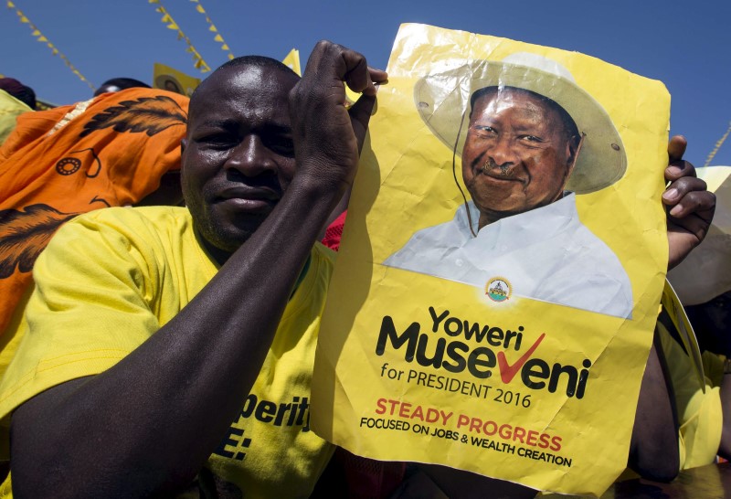 © Reuters. A supporter of Uganda's President Yoweri Museveni holds his campaign poster at a rally in Kololo grounds in capital Kampala